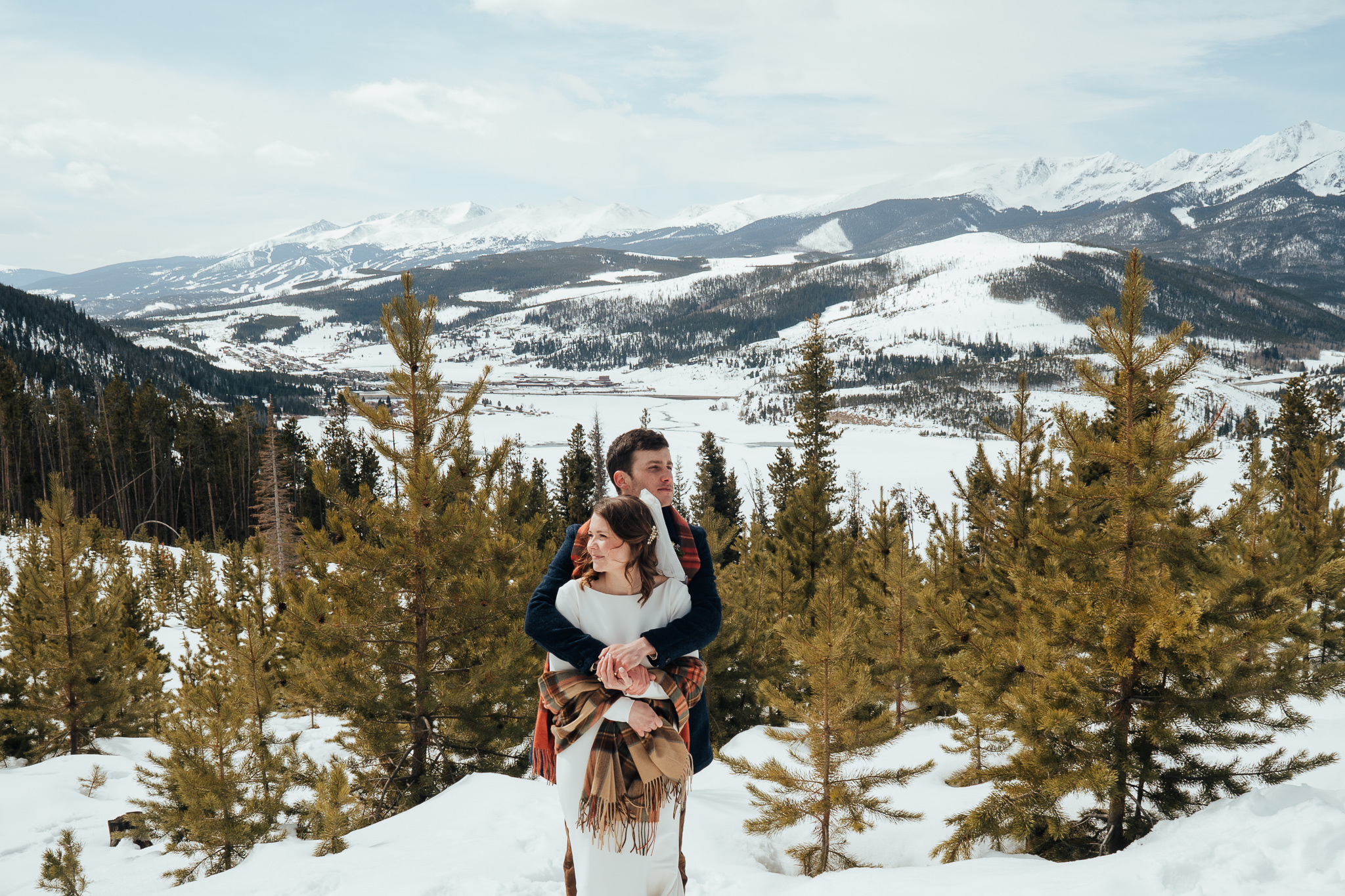 A couple embracing with the snow covered mountains surrounding them.