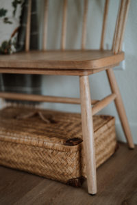 Wooden bench legs with a rectangular rattan basket underneath.